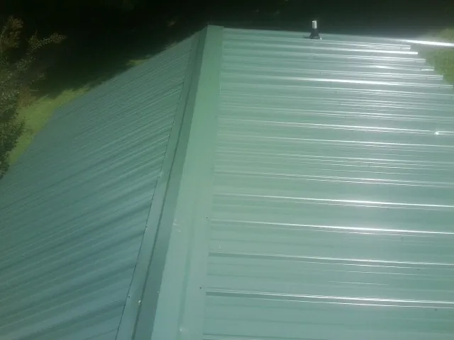 New green metal panels meeting at the ridge of a roof — Flat Roof Repair work by our crew in Woodbridge